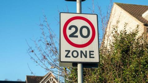 A 20 miles per hour speed limit zone sign in a residential area