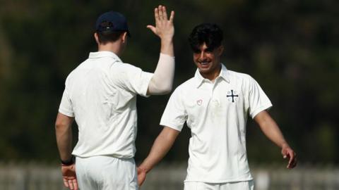 Nikhil Gorantla [right] goes to high five a team-mate while playing for Durham's second XI, with both players dressed in white cricket kits