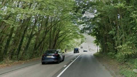 A general shot of the A23 at Redhill with cars on it and tree-lined road