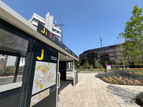 A newly built and opened public space in Swindon town centre, with a bus station and signage on the left. On the right are greenery including plants and a tree.