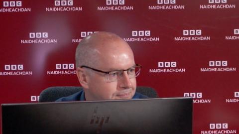 An t-Oll Conchúr Ó Giollagáin ann an stiùidio rèidio