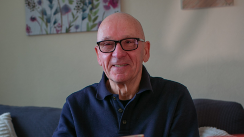 Paul Perkins. Paul is sitting down, bald and has glasses.