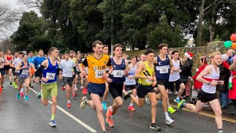 Large group of runners on a road on a grey day.