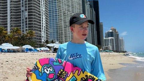 Gabrielius Misurenkovas at the beach holding a body board