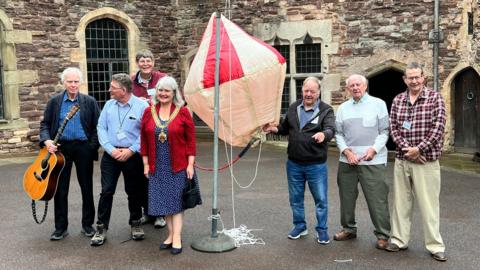 Seven people stood around a replica of the balloon at Berkeley Castle