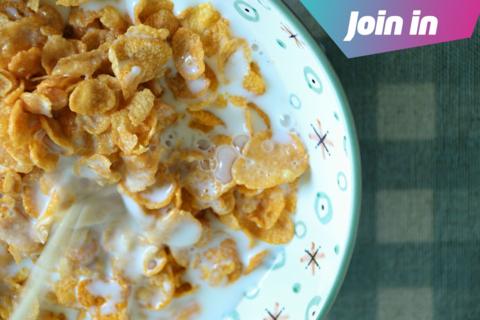 milk being poured on a bowl of cornflakes close up