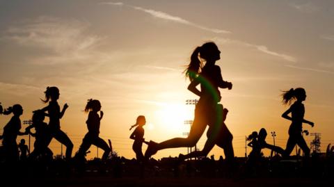 A group of people running at sunset.