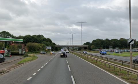 The Eggington junction of the A38 dual carriageway with petrol stations on both sides of the road, near the slip road exits from the bridge up ahead