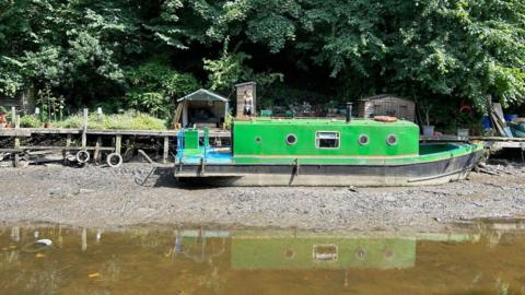 A green barge stranded on the mud