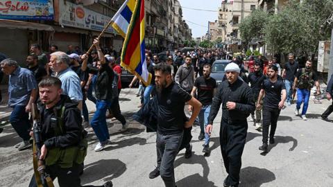 Gunmen take part in the funeral of seven people killed during overnight clashes between Syria's Druze community and security forces, in Damascus (30 April 2025)
