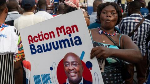 A supporter of Bawumia holds a placard reading the words 'action man Bawumia'.