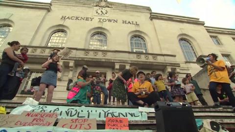A group of protesters outside Hackney Town Hall to protest against the cuts, there are banners that say "stop cuts" and "nurseries for everybody"