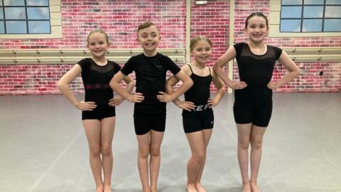 Four team members in their black dance uniform posing