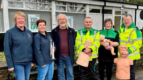 Blackburn with Darwen council leader councillor Phil Riley with St John Ambulance volunteers and Darwen Brass Band members outside the ambulance station building
