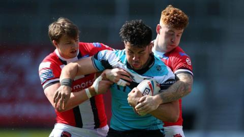 Goole Vikings player Andre Savelio holds onto the ball tenaciously in the blue, black and white of Hull FC as two Salford players try to rip it out of his hands