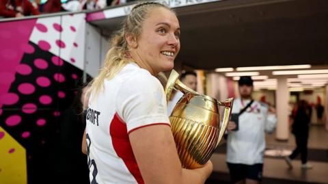 Zoe Stratford carrying the Women's Rugby World Cup trophy