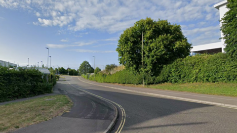 A general view picture of Houndmills Road in Basingstoke, a road in an industrial estate, which is fenced off by hedges and a few trees.