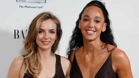 Jodie Comer and Katarina Johnson-Thompson pictured together at an awards ceremony where they are both wearing black dresses and smiling at the camera
