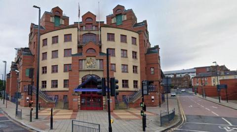 Leeds Magistrates Court: a redbrick court building pictured behind a set of traffic lights.