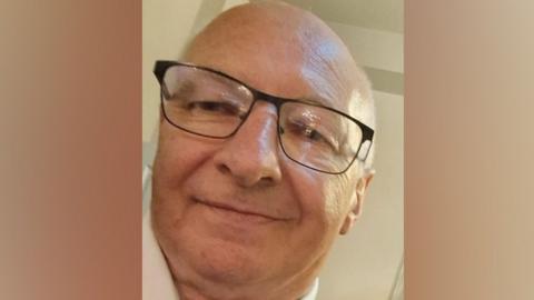 Photograph of Bernard Payne. He is smiling, bald and is wearing dark-rimmed glasses.