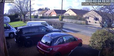 A view from a home in Christchurch, Cambridgeshire, showing cars in the foreground and a road 