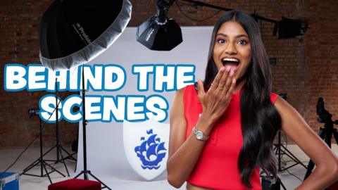 Shini gasps infront of a photoshoot set, text says 'Behind the scenes'.