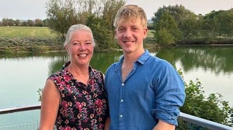 A mother and son stood in front of a lake