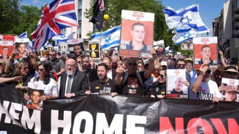 People holding banners, placards and images of hostages at the United We Bring Them Home march in London