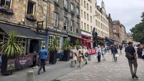 A cobbled and pedestrianised street with pubs and restaurants on one side.