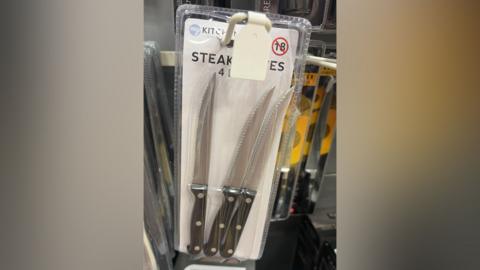 A pack of four steak knives on display in a shop, but the pack has been opened and one of the knives is missing.