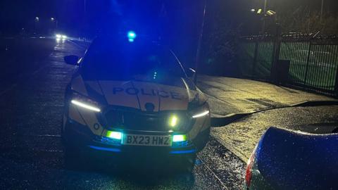 A police car on blue lights at night during a traffic stop