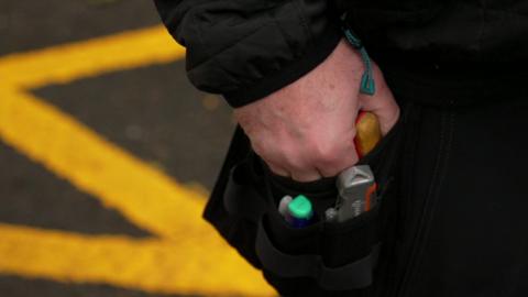 Close-up shot of hand in toolbelt. Tools can be seen in the black toolbelt.