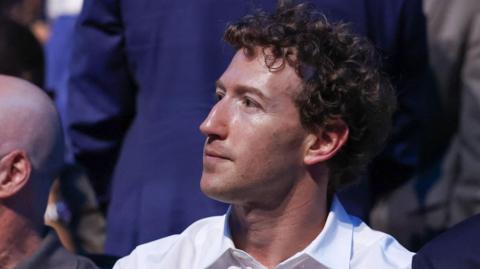 Mark Zuckerberg, wearing a white collared shirt while sitting in a crowd at the recent UFC event at the White House.