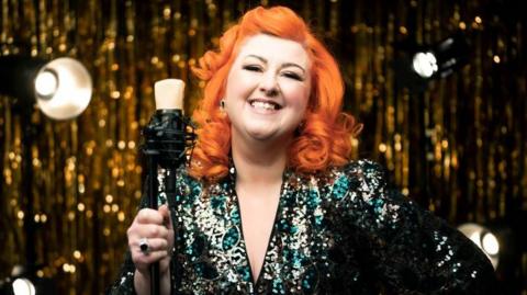 Michelle McManus, with bright orange hair wearing a sequin dress.
