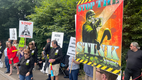 Campaigners opposing a landfill standing on a street holding placards