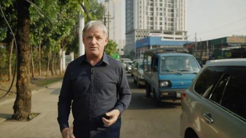 Jonathan Head walking next to queue of cars waiting for fuel