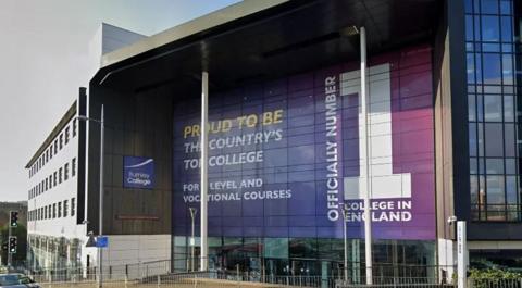 Street view image of Burnley College, a huge building with an imposing front entrance with white steel pillars and a large glass-fronted area with a huge purple sign saying 'Official no 1 college in England'