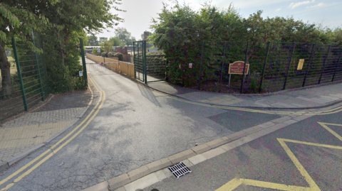 The front of Cleethorpes' Signhills Academy, with double yellow lines, chevrons, and "no parking" signs on the road