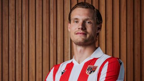 Svante Ingelsson crosses his arms as he poses for a picture in his red and white striped Stoke City shirt
