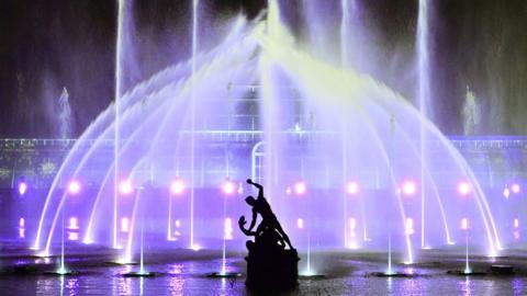 The Palm House at Kew Gardens is illuminated with a light show during a preview for the Christmas at Kew event on November 15, 2022 in London, with the Hercules statue in a silhouette in front of it. 