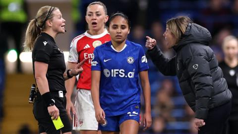 Sonia Bompastor, Manager of Chelsea, reacts in front of Katie McCabe and Alyssa Thompson after being shown a yellow card by referee Frida Mia Klarlund 