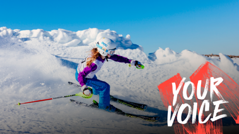 A child skiing down a mountain. She is wearing a white helmet and goggles, with hair hanging out of the back.