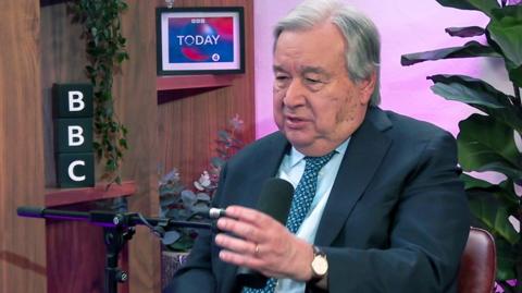 Antonio Guterres gestures as he talks into a microphone with a plant in background during an interview with BBC