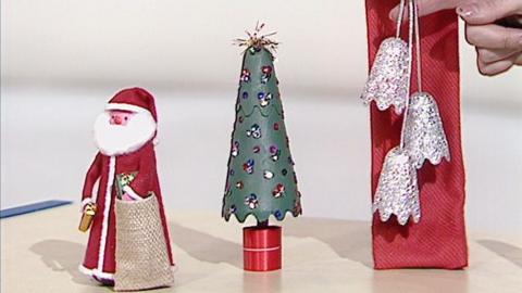 A Santa, Christmas tree, and bells made from sauce bottles.