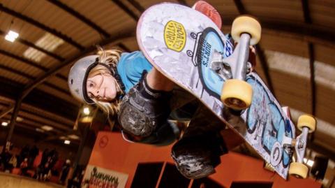 Jaxon Popovic holds a skateboard in mid-air