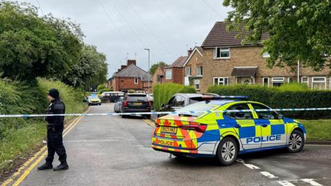 A police car behind a cordon in a residential road