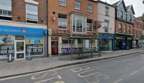 A view of the Golden Ball pub from the High Street in Bridgwater. The pub has red signs and a red door with beige walls.