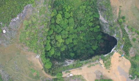 Aerial photo of a sinkhole dropping away in the middle of the forest in China's Guangxi province