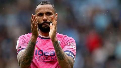 Kyle Bartley in his pink West Bromwich Albion shirt claps the fans after a game