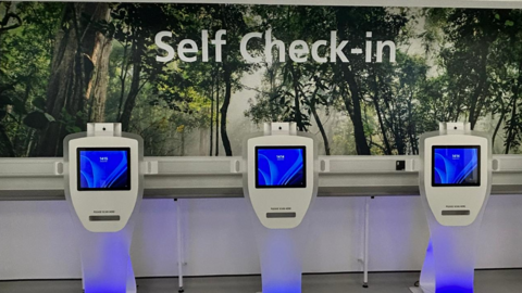 Three tablets in a waiting area. A sign on the wall says "Self Check-in".
